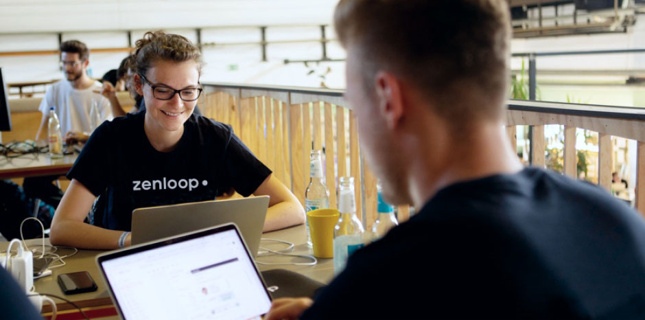 image of two people sitting across each other looking at their laptops